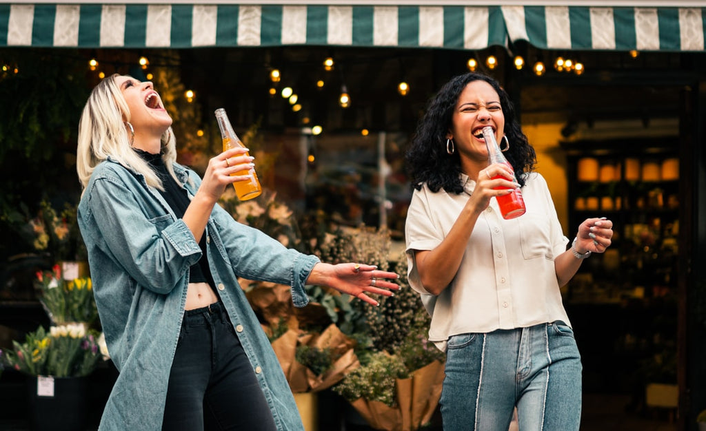 Women laughing and enjoying Portuguese sodas outside of flower shop